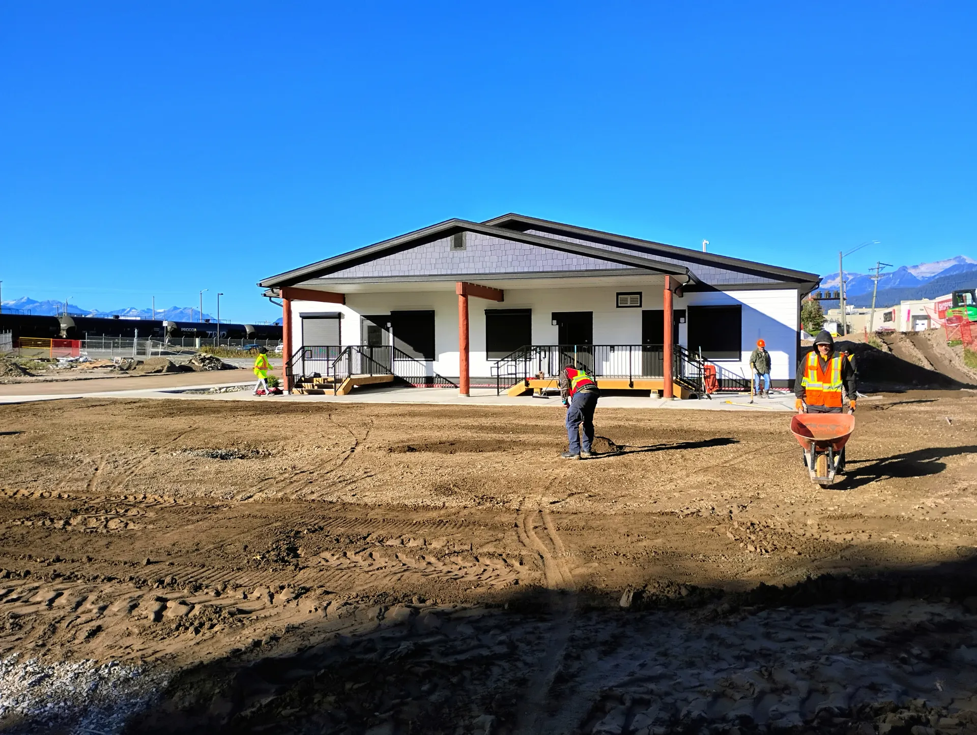 The new daycare building with bare prepared ground and a crew working in front