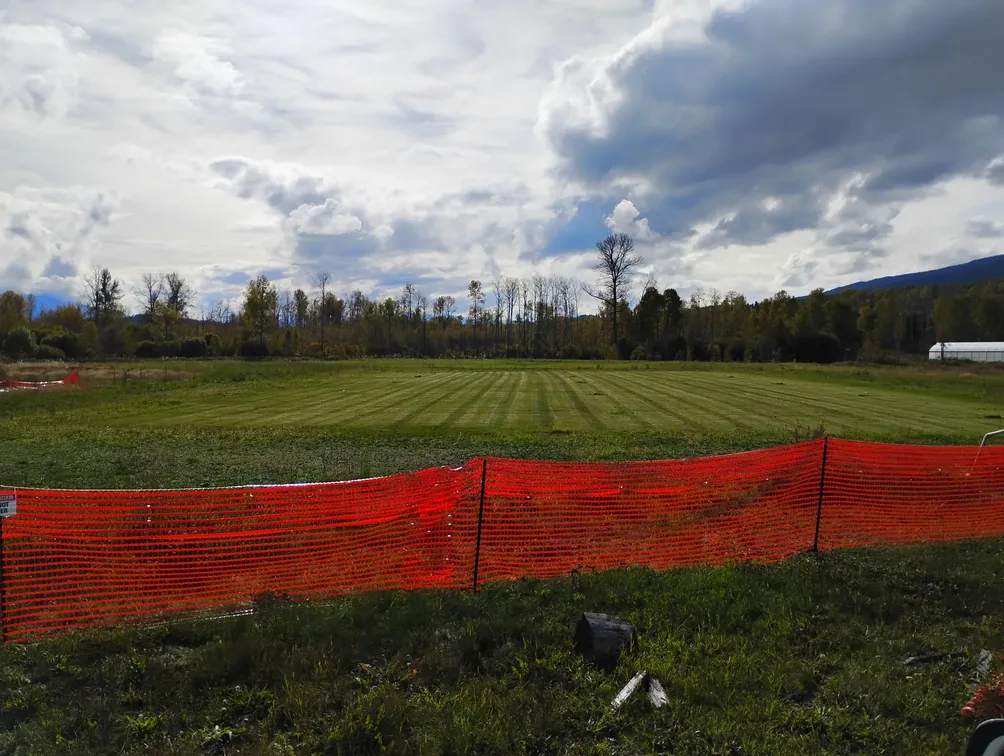 A new green field behind orange construction fencing