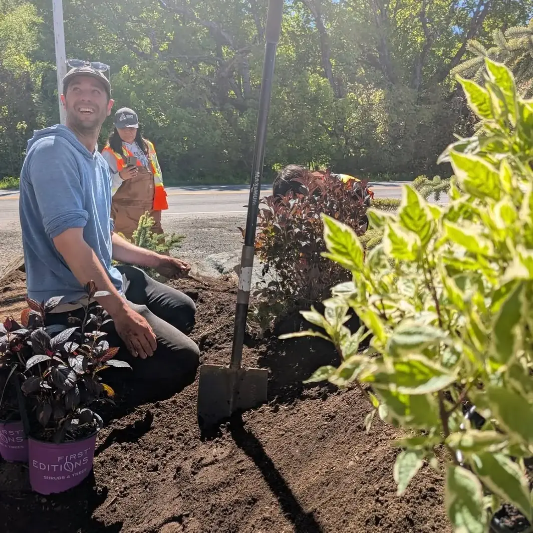 Wesley smiling while planting a bed with a student crew
