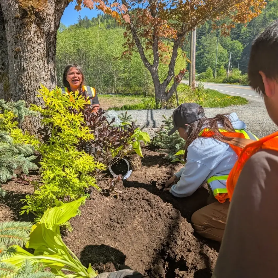 Students and a community elder planting a boulder bed together