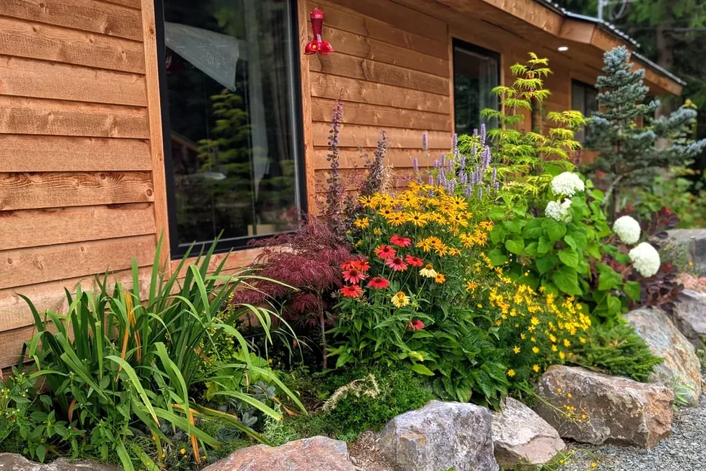 A planted bed against the cedar building at the Kulspai Learning Village