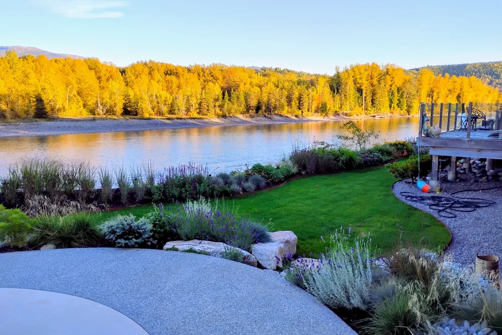 A green lawn and planted borders running down to the river at River House